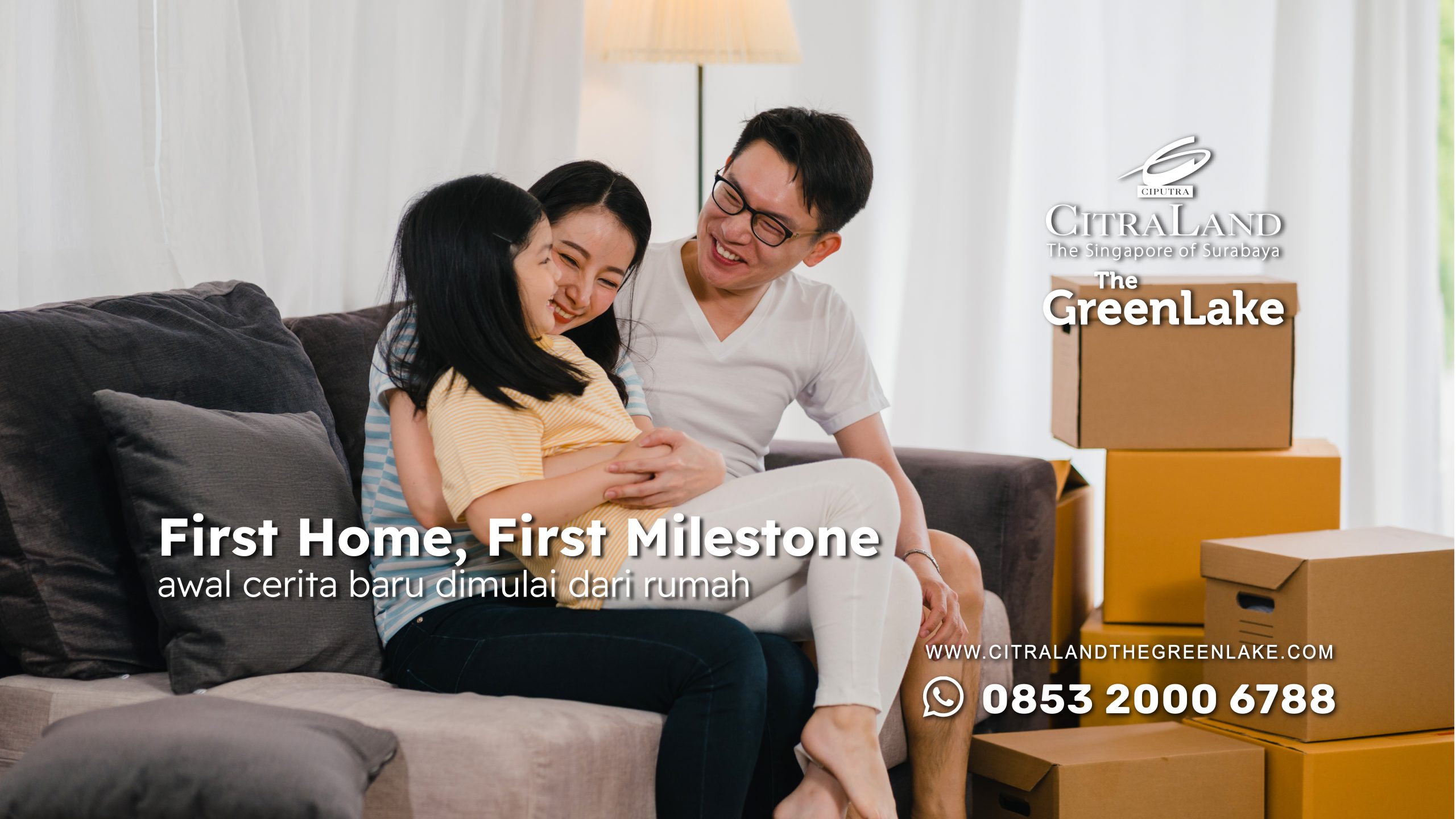 Family of three cuddles on a sofa in a bright living room with packed moving boxes, celebrating a new home purchase/s move-in day.